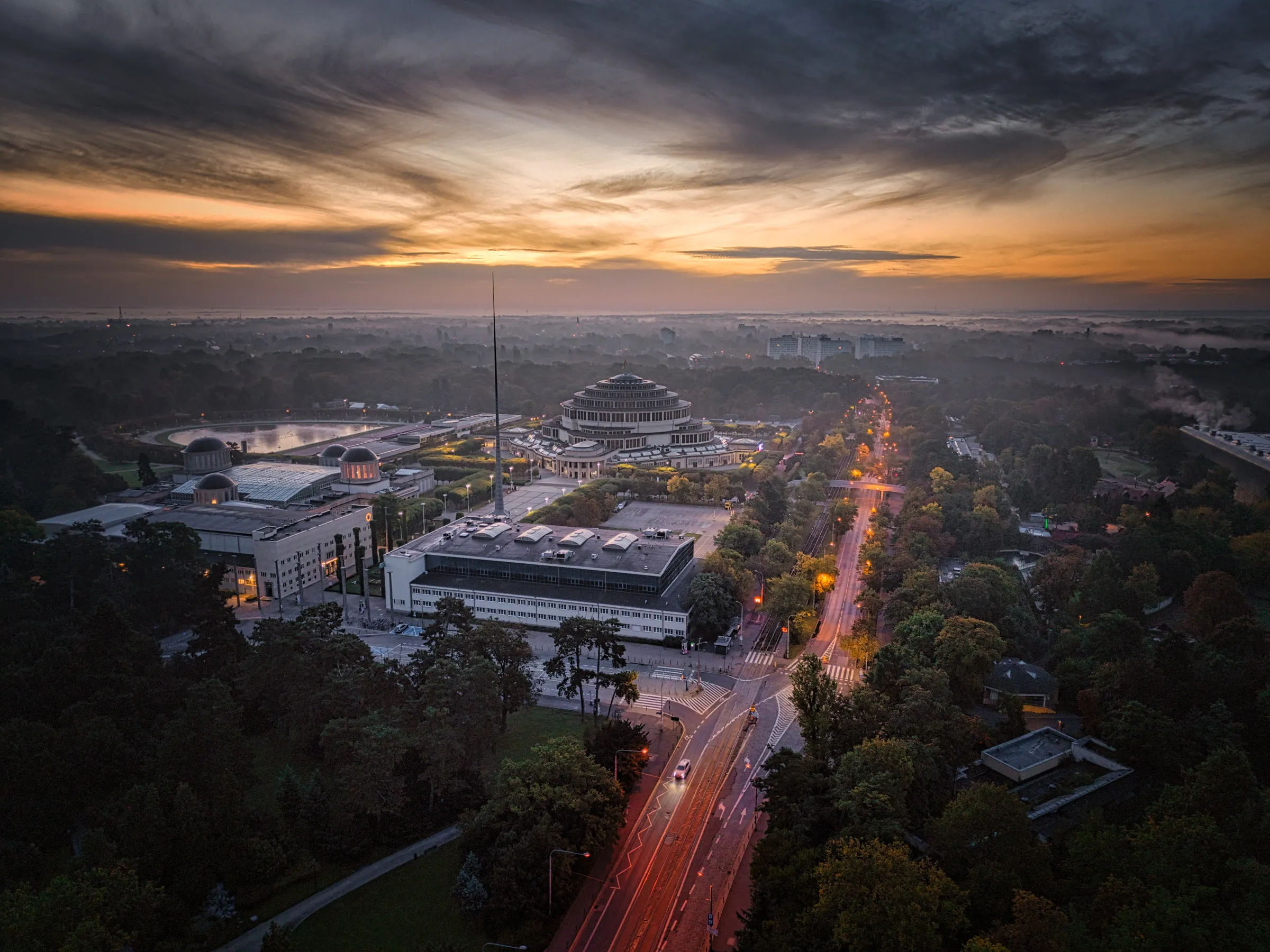 Okolice Hali Stulecia we Wrocławiu o świcie, ulica ze smugami świateł, widok z drona